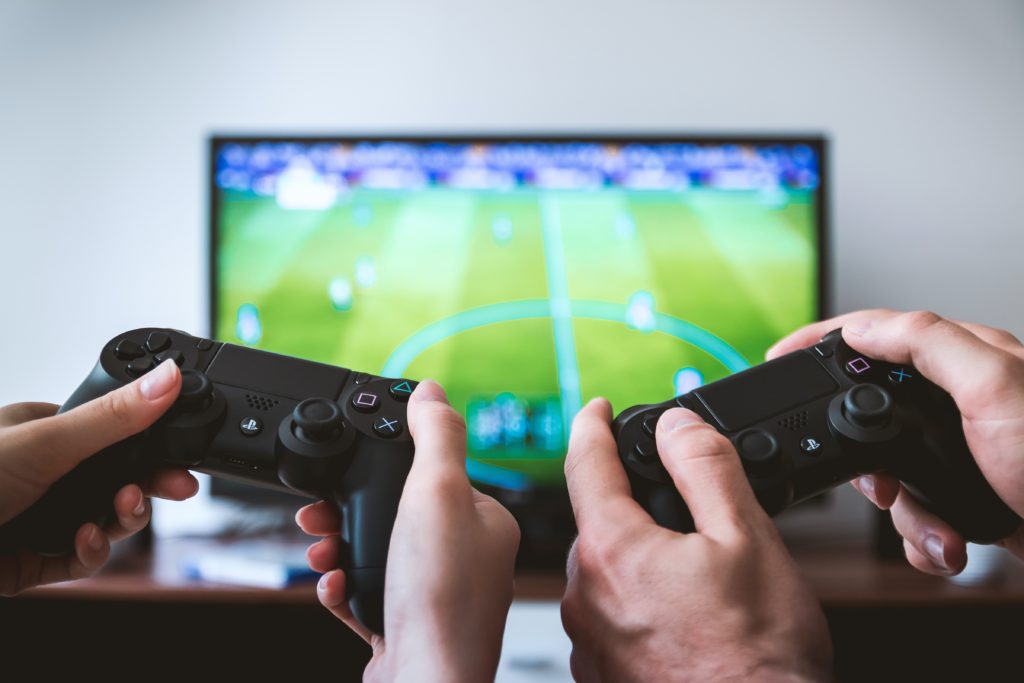 People playing Fifa on a Playstation in a garden games room 